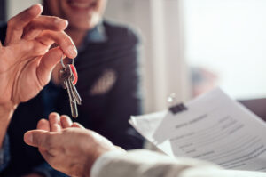 a homeowner well-versed in Capital Gains Tax Letting Relief passing their keys to an estate agent after the sale of their property
